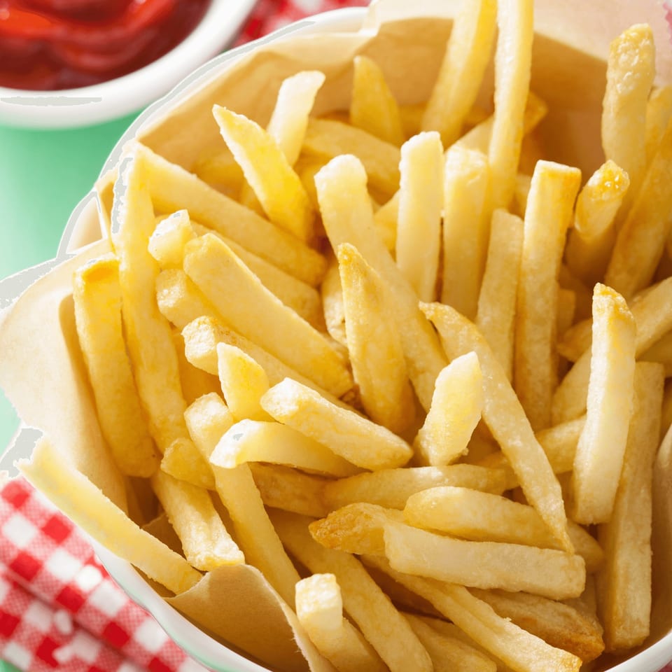 Golden french fries in a paper-lined cup with a side of ketchup.